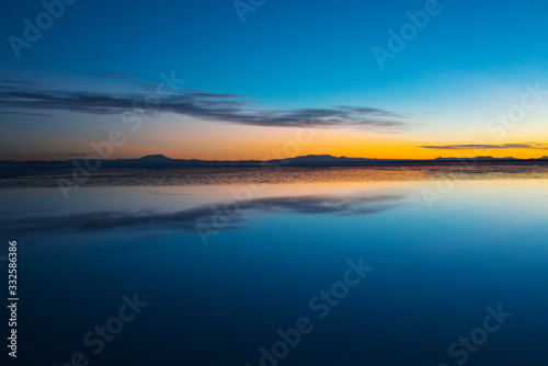 Sunrise on Salar de Uyuni in Bolivia covered with water, salt flat desert and sky reflections