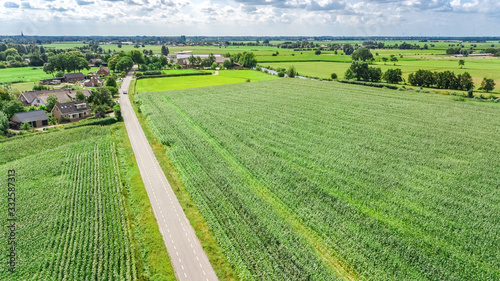 Aerial drone view of green fields and farm houses near canal from above  typical Dutch landscape  Holland  Netherlands