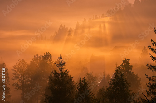 Picturesque fairy foggy sunrise over the village in mountains.