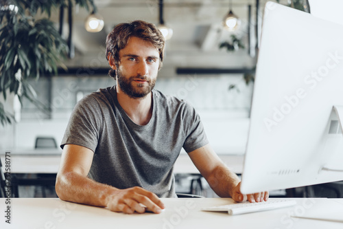 Bearded man freelancer using computer in a modern coworking place. Freelance business concept photo