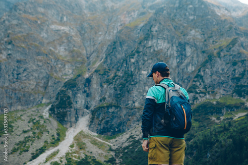 man with backpack looking at lake in mountains