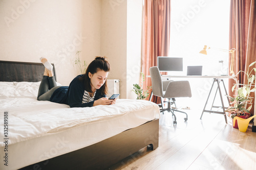 Photography woman on bed surfing internet on phone reading news