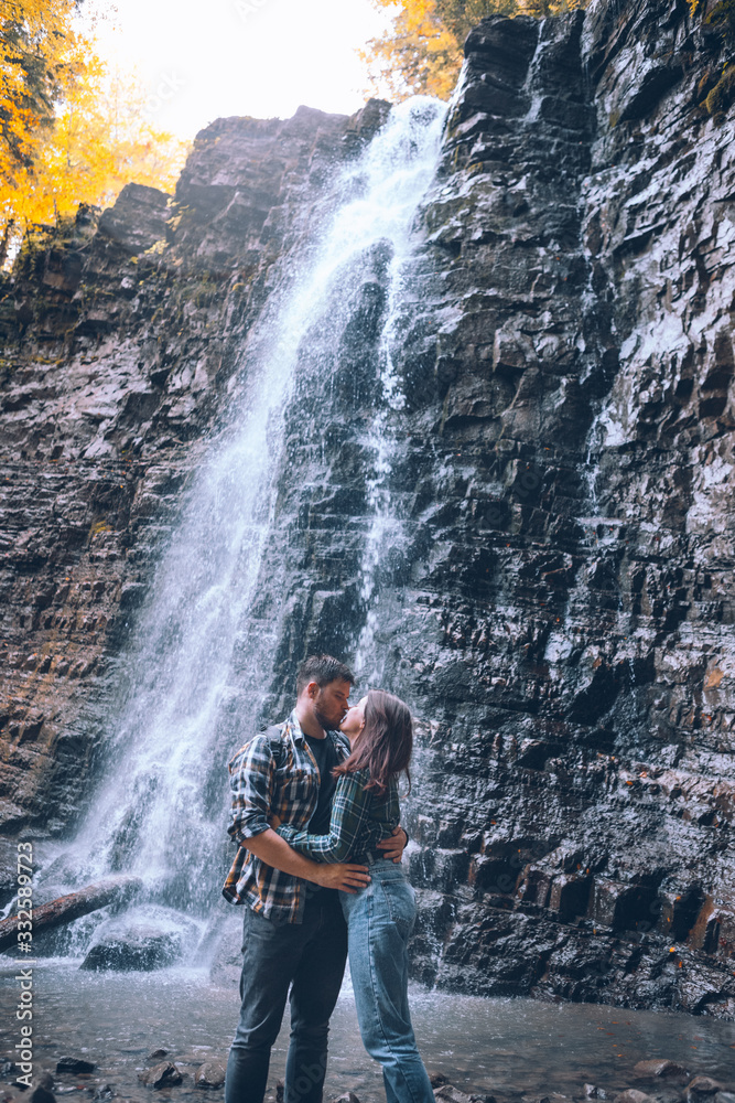 couple in front of waterfall autumn season