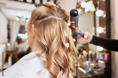 Blonde girl in a beauty salon doing a hairstyle. Close-up.