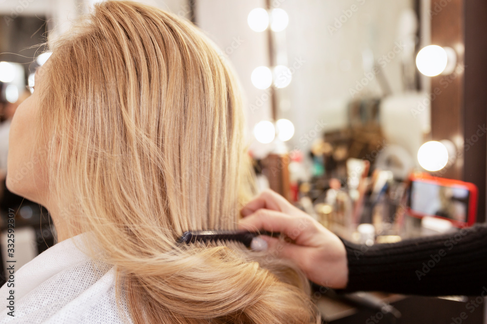 Fototapeta premium Blonde girl in a beauty salon doing a hairstyle. Close-up.