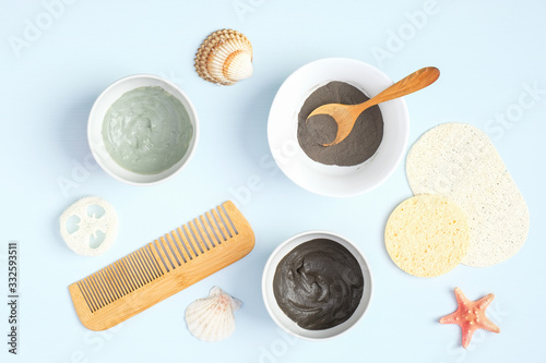 SPA natural organic beauty products for face skin care and treatment. Top view. Cosmetic clay mask and powder in bowls, luffa sponge, hair comb on pastel blue background.