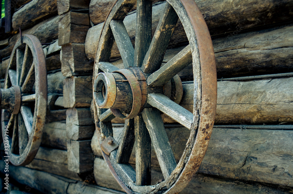 old wooden cart wheel hanging under the roof of the house