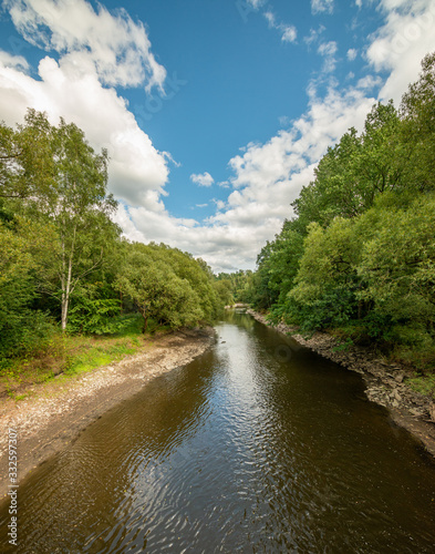 river with low water level in forest with blue cloudy sky