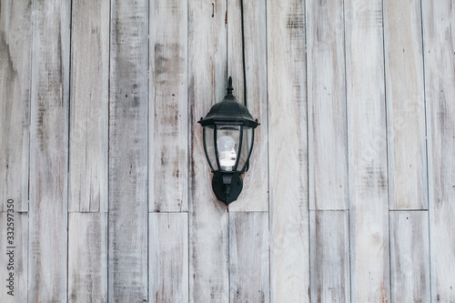 Fototapeta Naklejka Na Ścianę i Meble -  Wood table painted white, wooden texture.Wall lamp with yellow shade from canvas . The lamp shines in the dark . Vintage Wall Lamp . light bulb design in vintage style on wall . antique lamp . close u