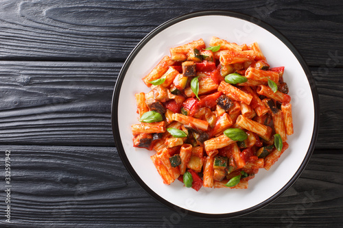 Tortiglioni pasta diet recipe with summer vegetables and basil in tomato sauce close-up in a plate. Horizontal top view