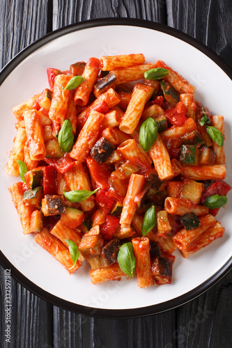 Vegetarian Tortiglioni pasta with vegetables and basil in tomato sauce close-up in a plate. Vertical top view