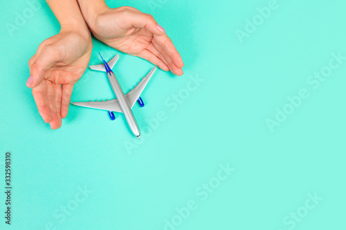  Beautiful young woman s hands holding plane    on pastel  background .