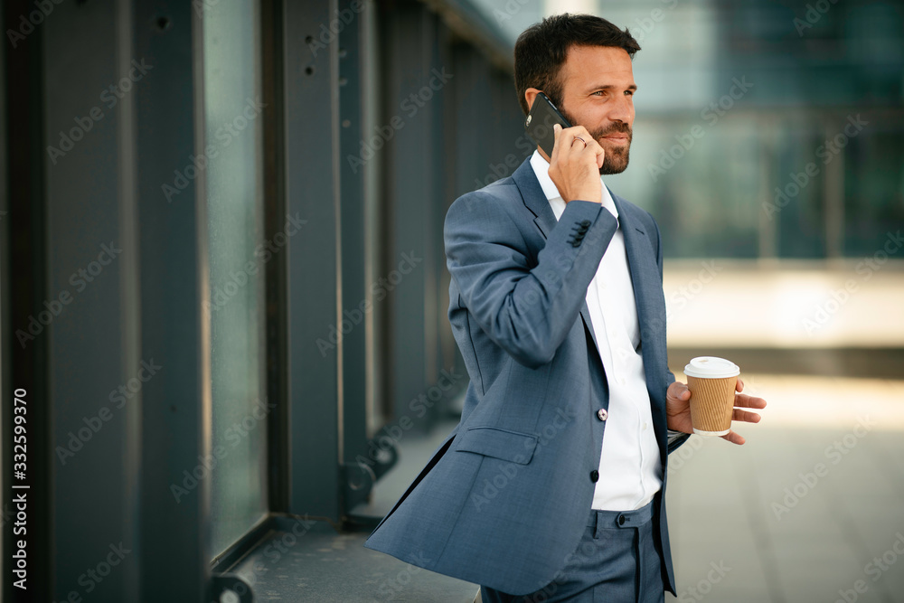 Young handsome man drinking coffee outdoors. Businessman in a blue suit. Young handsome man drinking coffee outdoors. Businessman in a blue suit.