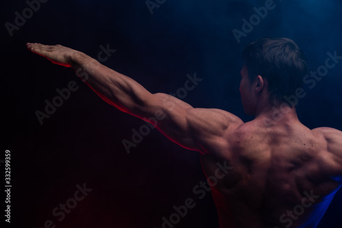 Muscular man showing muscles isolated on the black background close up. Concept of healthy lifestyle 