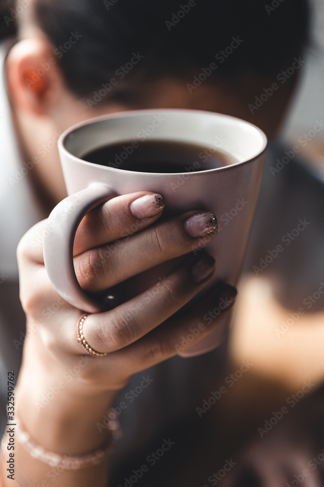 Woman in the morning drinks coffee and reads old book in a white shirt. Education, drink. manicure Woman in the morning drinks coffee and reads old book in a white shirt. Education, drink. manicure