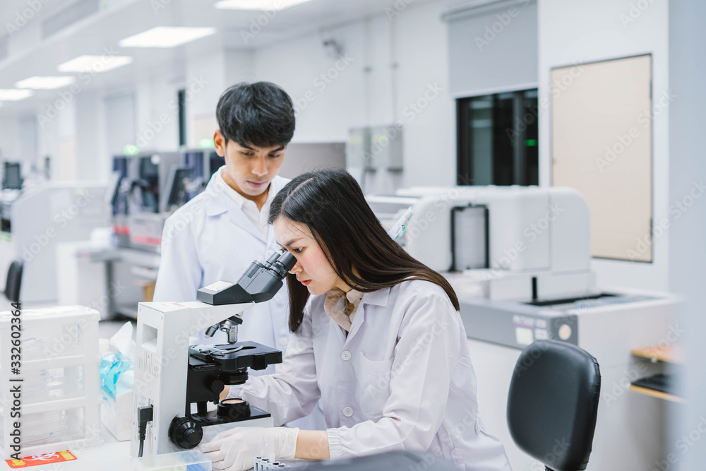 Two medical scientist working in Medical laboratory , young female scientist looking at microscope. select focus in young female scientist Two medical scientist working in Medical laboratory , young female scientist looking at microscope. select focus in young female scientist