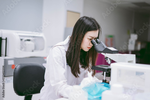 young female scientist looking at microscope in medical laboratory © Near