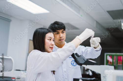 Two young medical  scientist looking at test tube in medical laboratory   select focus on male scientist