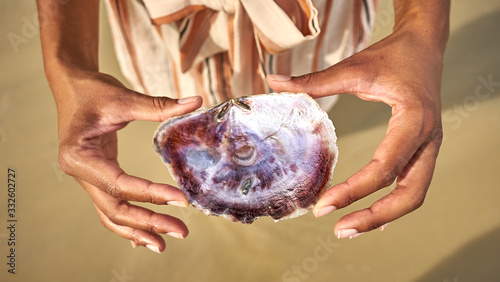 Hands holding seashell with beautiful Mother of Pearl at beach of Port Barton, Palawan, Philippines photo