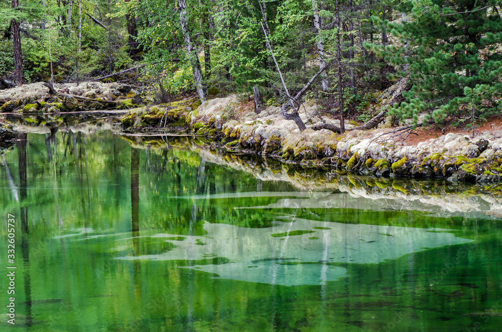 Small forest lake with greenish water in the autumn forest, lava lake Small forest lake with greenish water in the autumn forest, lava lake