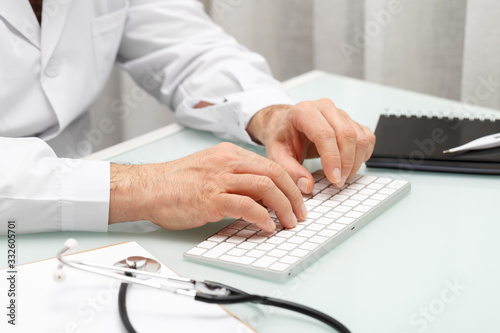 Male doctor seating at the table typing