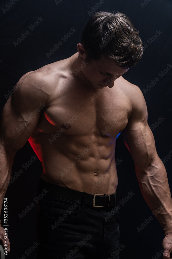 Muscular man showing muscles isolated on the black background with colored smoke. Concept of healthy lifestyle Muscular man showing muscles isolated on the black background with colored smoke. Concept of healthy lifestyle