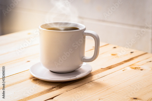 hot coffee on wood table with smoke in the mug cup with natural light in the morning