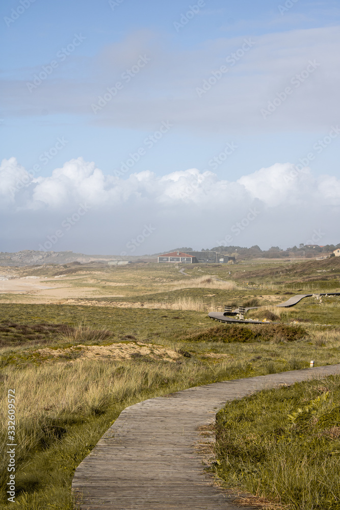 Obraz premium Dunes of Corrubedo, beach and walk, Galicia, Spain. Beautiful wooden walk path in dune beach in the north of Spain. 