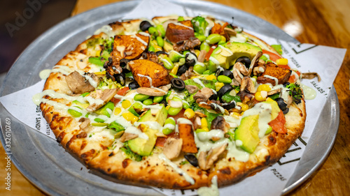 Pizza topped with black olives, mushrooms, golden corn, broccoli, avocado, edamame, and sweet potatoes