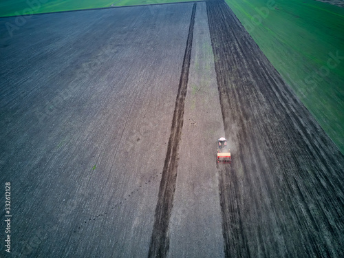 Tractor in a field performing spring sowing., top view from drone pov photo