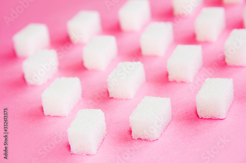 square white pieces of natural refined sugar on a pink background