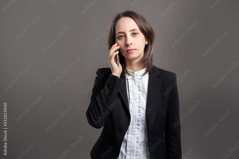 Portrait of wonderful young business woman talking on cellphone, poseing on isolated gray background Portrait of wonderful young business woman talking on cellphone, poseing on isolated gray background