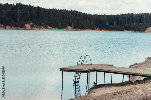 A dock near a lake in between a forest. Moody calm tones.  Sandy beach. Located in Dubkalnu Karjers, Ogre photo