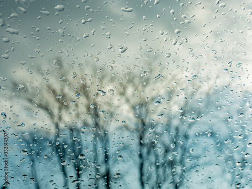 Wet window with rain drops and a cloudy sky outside.