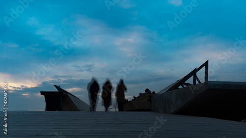 Silhouettes of people on the bridge long exposure photo. city people