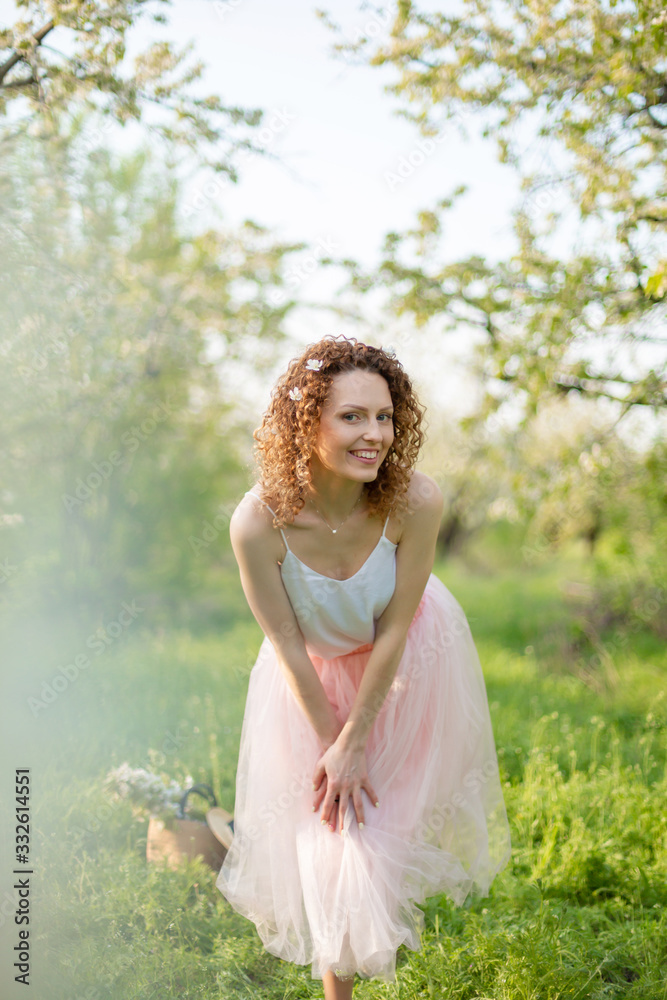 Young attractive girl walks in spring green park enjoying flowering nature Young attractive girl walks in spring green park enjoying flowering nature