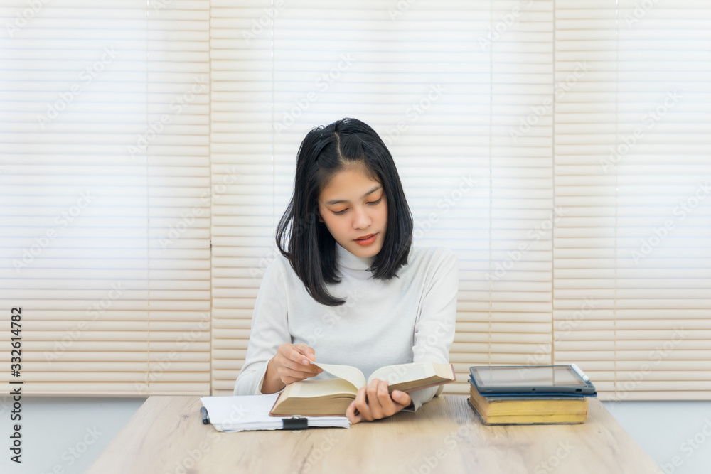Portrait of a young cheerful Asian female university student studying in self study room in the university library to do her assignment and prepare for examination. Portrait of a young cheerful Asian female university student studying in self study room in the university library to do her assignment and prepare for examination.