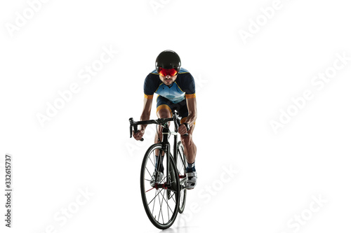 Triathlon male athlete cycle training isolated on white studio background. Caucasian fit triathlete practicing in cycling wearing sports equipment. Concept of healthy lifestyle, sport, action, motion. © master1305