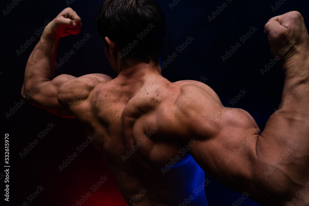 Muscular man showing muscles isolated on the black background with colored smoke. Concept of healthy lifestyle Muscular man showing muscles isolated on the black background with colored smoke. Concept of healthy lifestyle