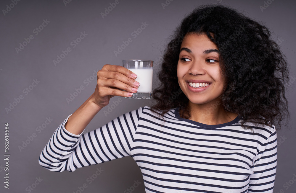 Joyful smiling young black lady with a glass of milk in her hand. Joyful smiling young black lady with a glass of milk in her hand.