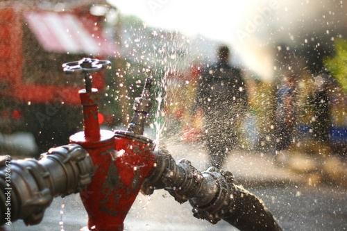 Water splashes from the fire hose and hydrant connections. Firefighters Work Concept photo