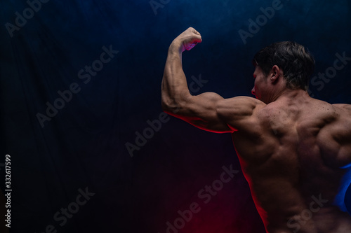 Muscular man showing muscles isolated on the black background. Concept of healthy lifestyle 