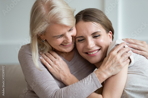 Smiling older mother and adult daughter hugging and laughing, family having fun together, young woman and mature mum enjoying tender moment, expressing love and support, two generations close up
