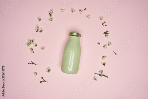 green bottle of smoothy on pink background with small flowers