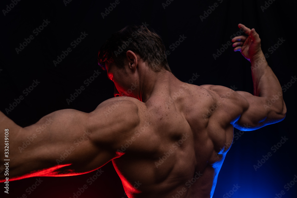 Muscular man showing muscles isolated on the black background with colored smoke. Concept of healthy lifestyle Muscular man showing muscles isolated on the black background with colored smoke. Concept of healthy lifestyle