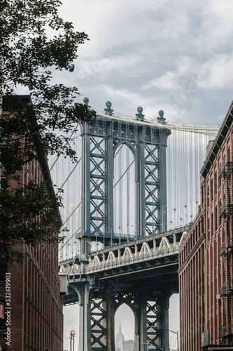 Manhattan bridge seen from a narrow alley enclosed by two brick buildings on a sunny day in summer © michelle7623