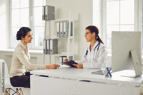 Doctor woman pediatrician gynecologist talking client sitting at a table in a clinic office. photo