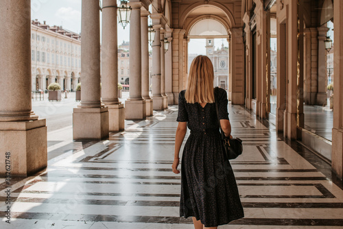 A beautiful woman with blond hair walks through the streets of the city. Girl enjoy holidays in Europe. Beautiful historical architecture. Italian weekend. Travel to Turin, Italy. Adventure lifestyle