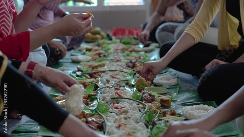 kembulan. woman friends smiling looking at camera while having lunch together. asian javanese traditional eating together sitting on floor
