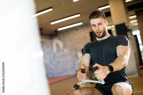 Young man using seated row machine in the gym